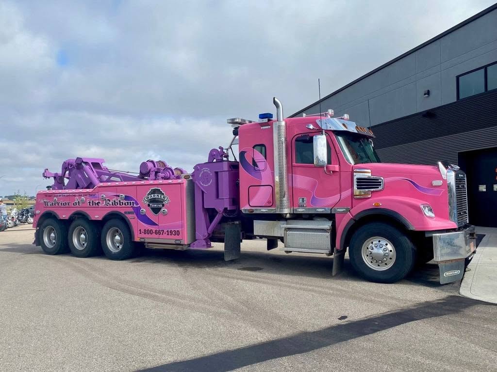 The Warner Towing 'Warrior of the Ribbon' pink-and-purple heavy-duty tow truck parked outside Prairie Harley-Davidson at the 2025 Breast Cancer Awareness Ride